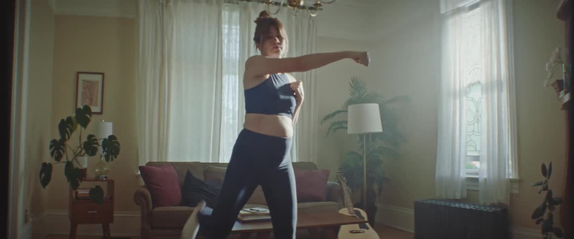 Pregnant woman with sport bra and tights works out in the living room at home