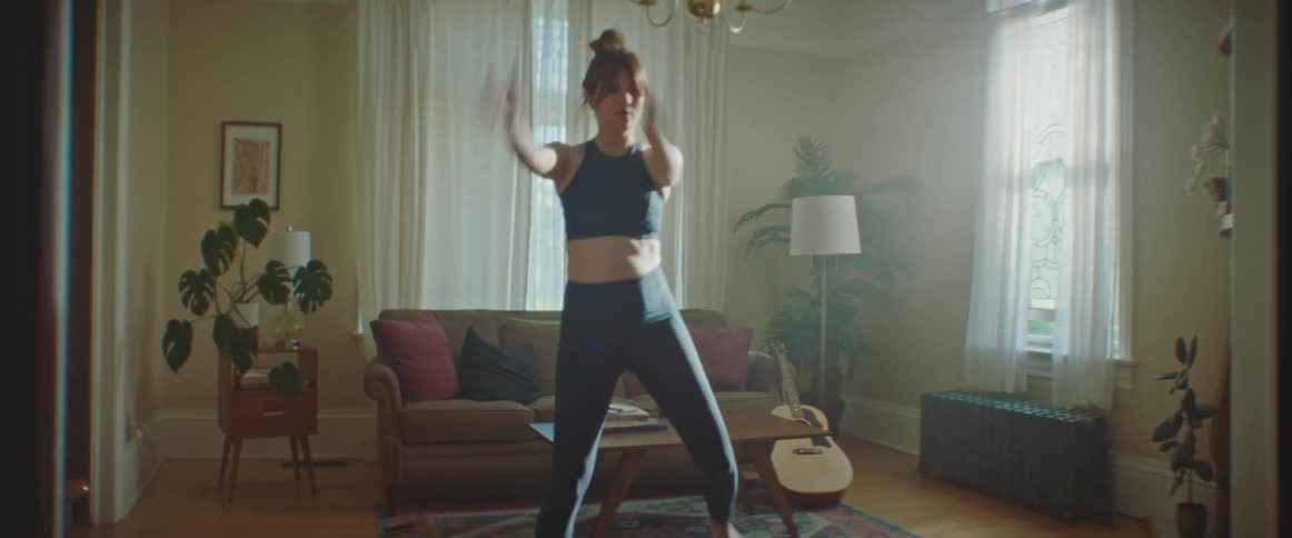 Pregnant woman with sport bra and leggings works out in the living room at home