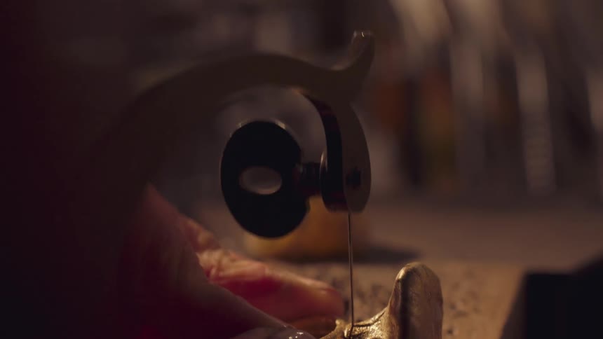 A persons hand using a corded tool to cut an object