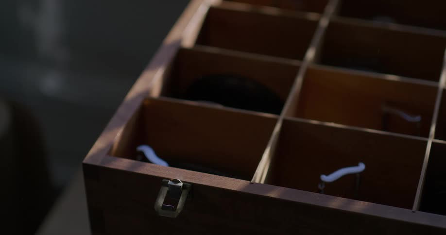 A human hand opens a wooden box and takes out an object from inside and then closes the box