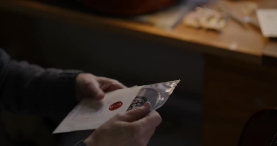 A persons hand opening a paper envelope and taking out an object inside