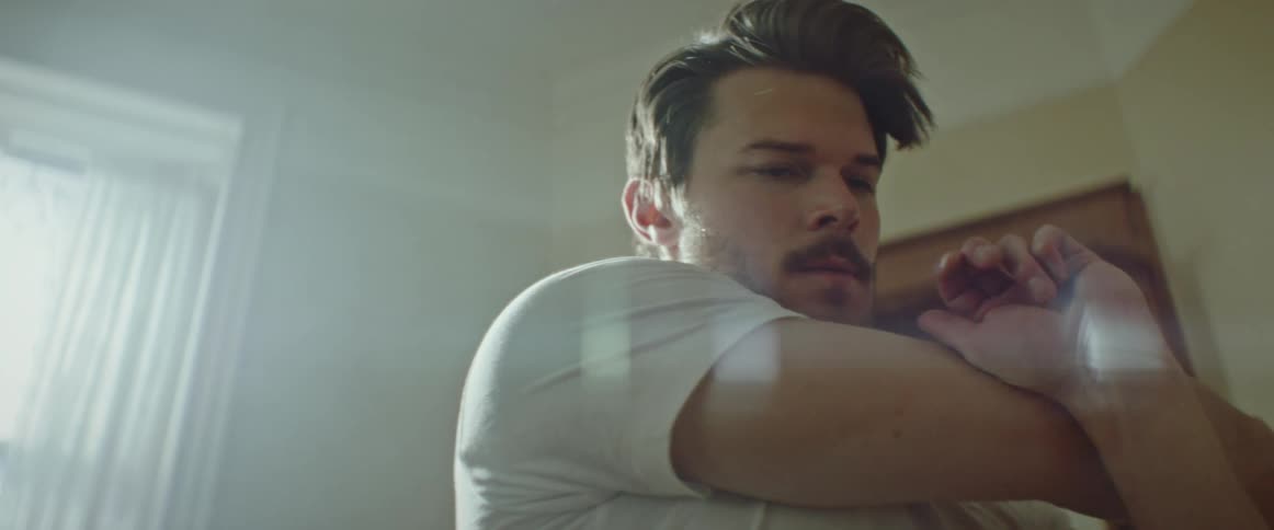 A man stretches and rolls his shoulders in a house during the day
