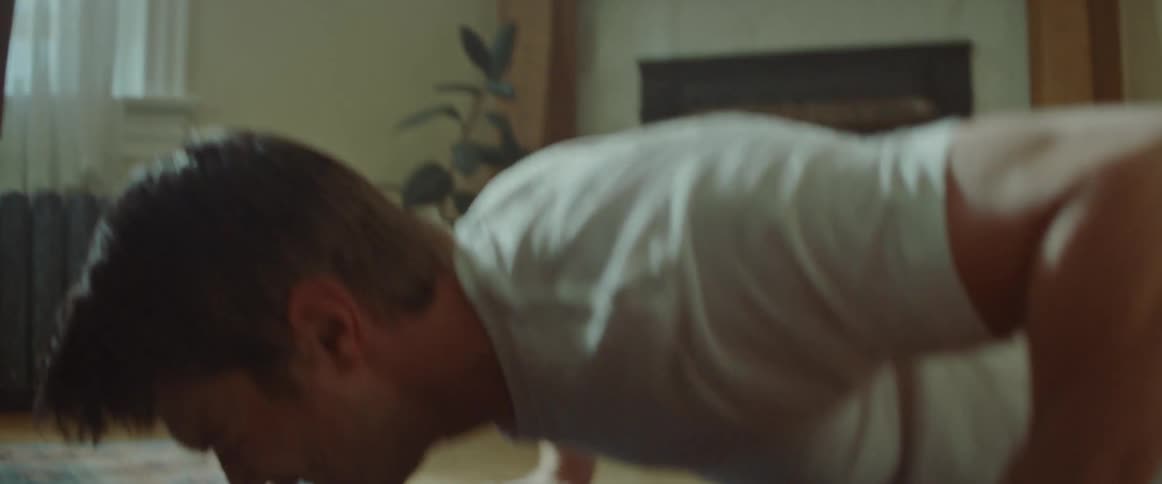 Male does pushups on an exercise mat in front of a coffee table in the living room