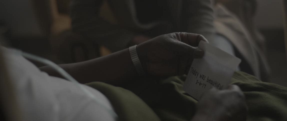 A woman hands an envelope of photos to an elderly man