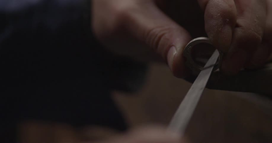 A person files down the inside of a ring