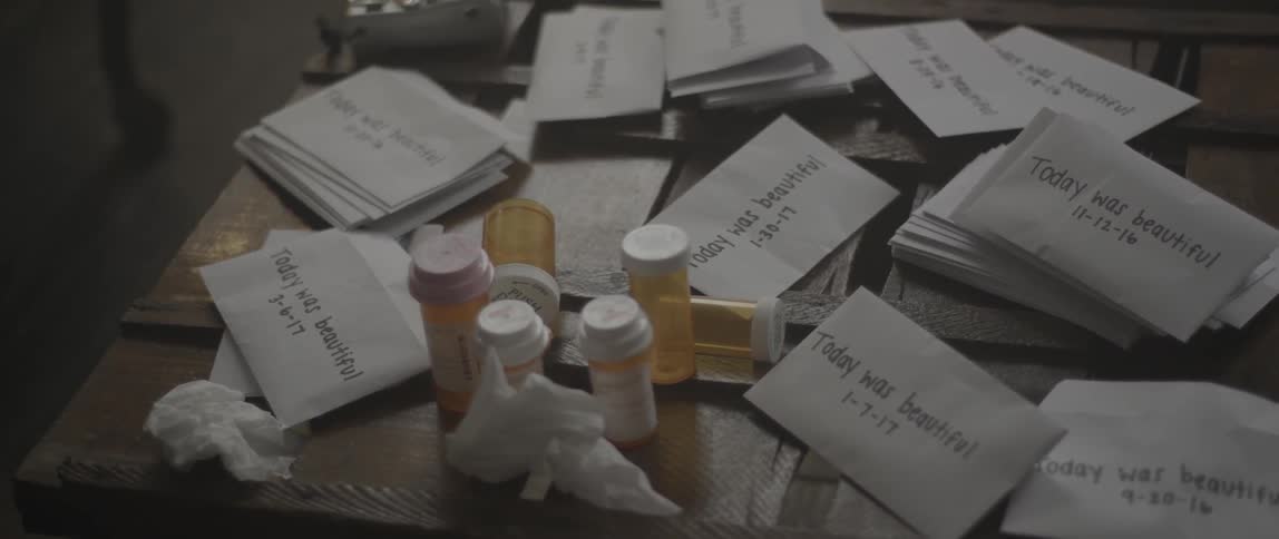 A person sets down a dated envelope next to some empty pill bottles