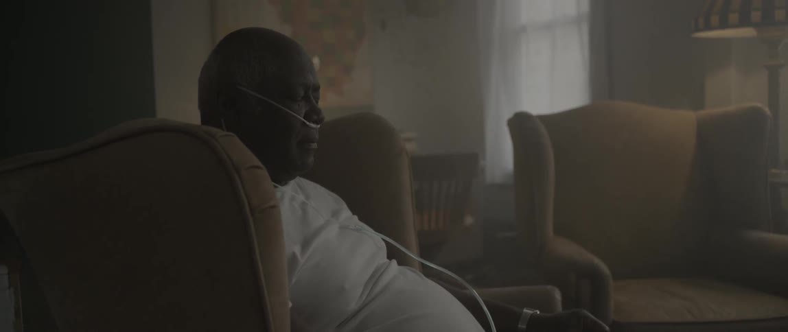 A man sits in a chair with his eyes closed