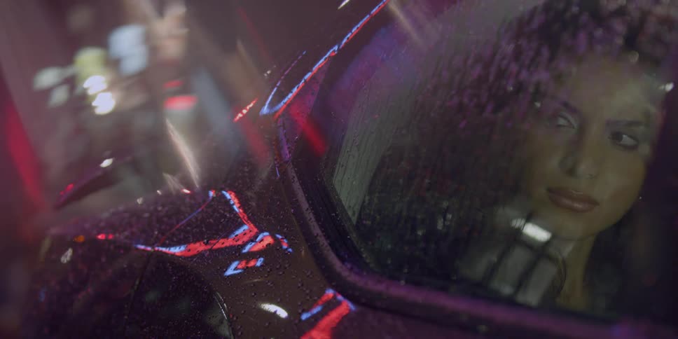 Woman looks out car window at a busy rainy night