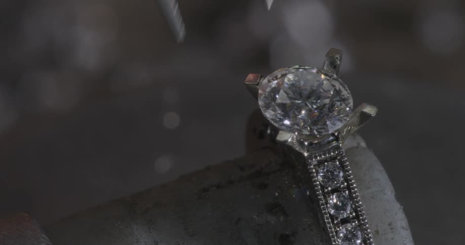 A jeweler places a diamond in a setting
