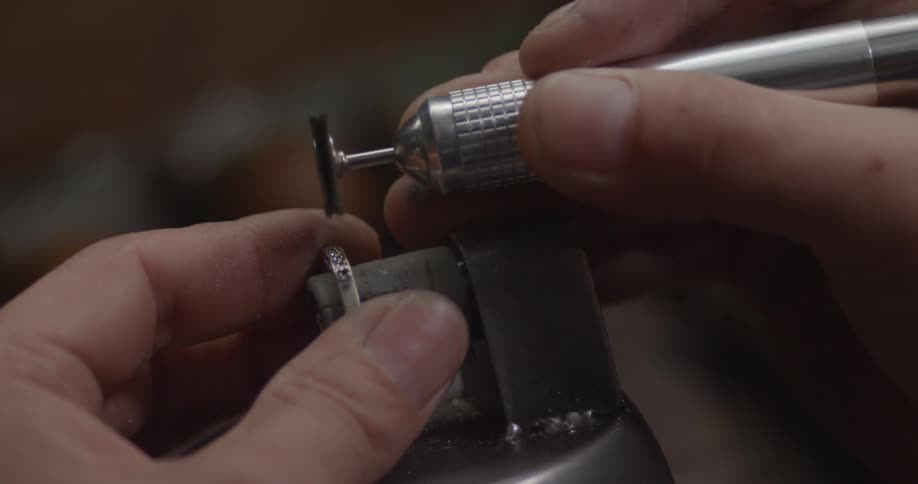 A man buffs a ring with a small tool
