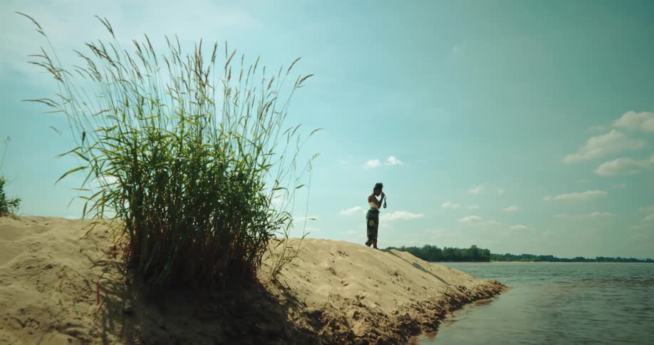 Woman walking on the sand and taking photos of the river