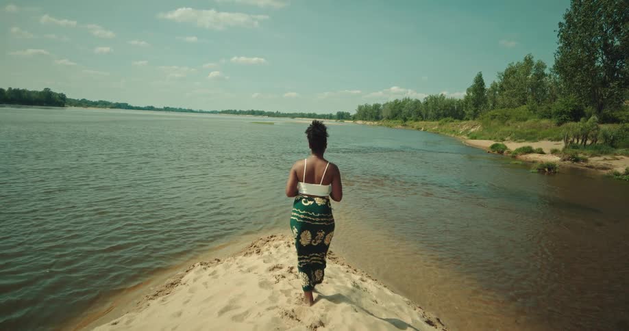 A black woman walking on the bank of the river to and fro