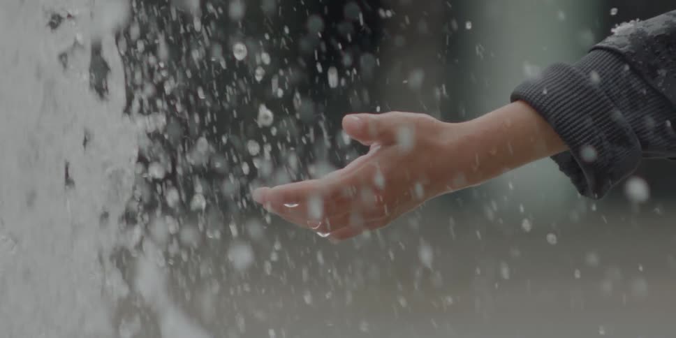 A person holds their hand out into a fountain of water