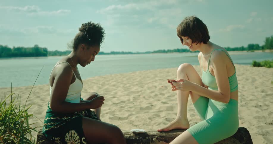 Two friends are playing cards on a log