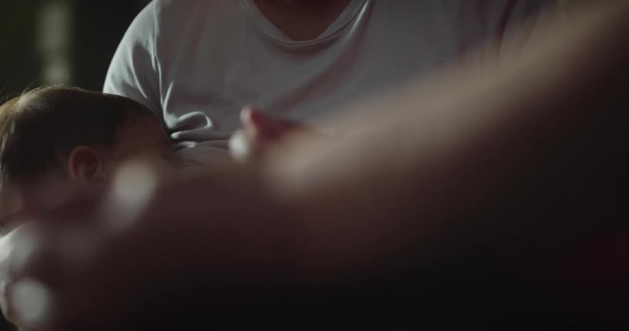 Mother breastfeeding her child while talking to another person beside her