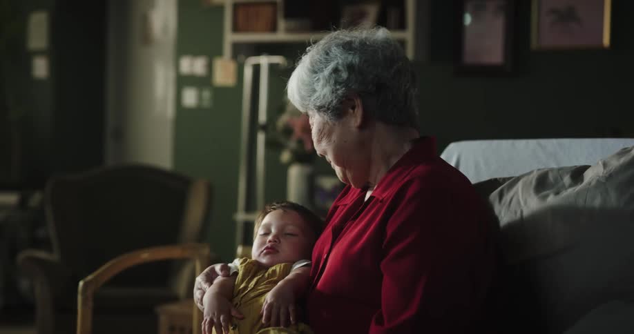 A grandmother cradling her sleeping grandson in her arms