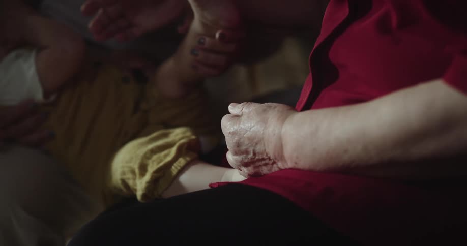 Grandmother giving a foot massage to a baby being breastfed by the mother