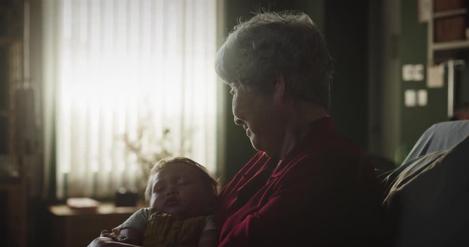 A grandmother holds her sleeping granddaughter in her arms