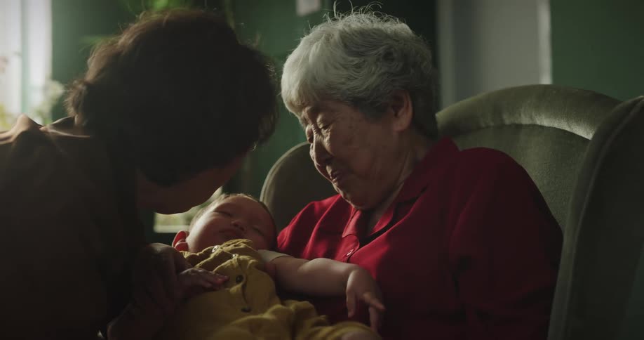 A grandmother holding her grandson sitting in an armchair
