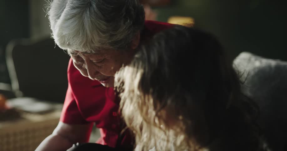 A grandmother is reading a book to her granddaughter