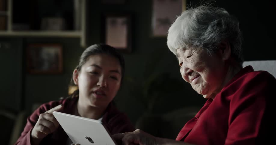 Two asian women look at tablet computer and gesture