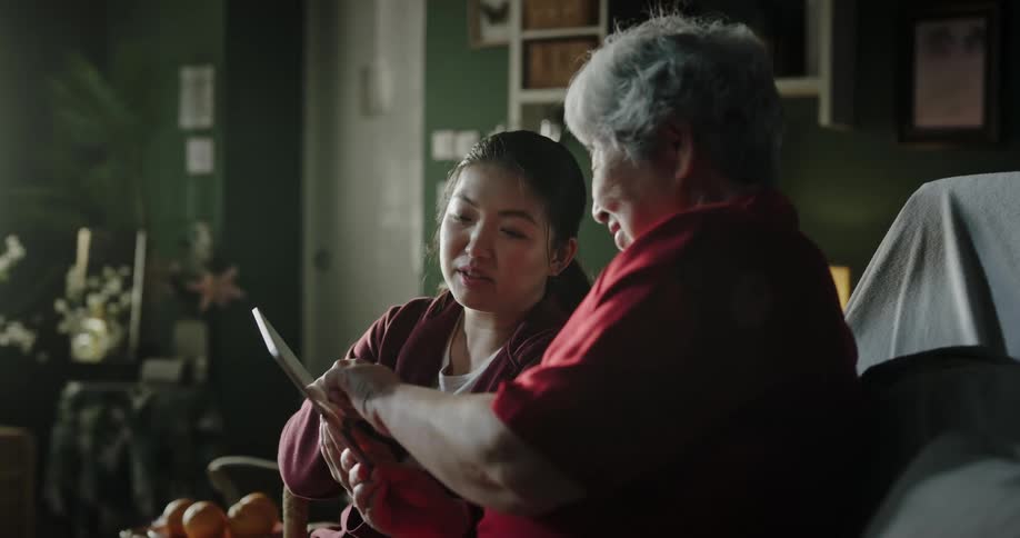 Daughter teaching mother how to use a tablet