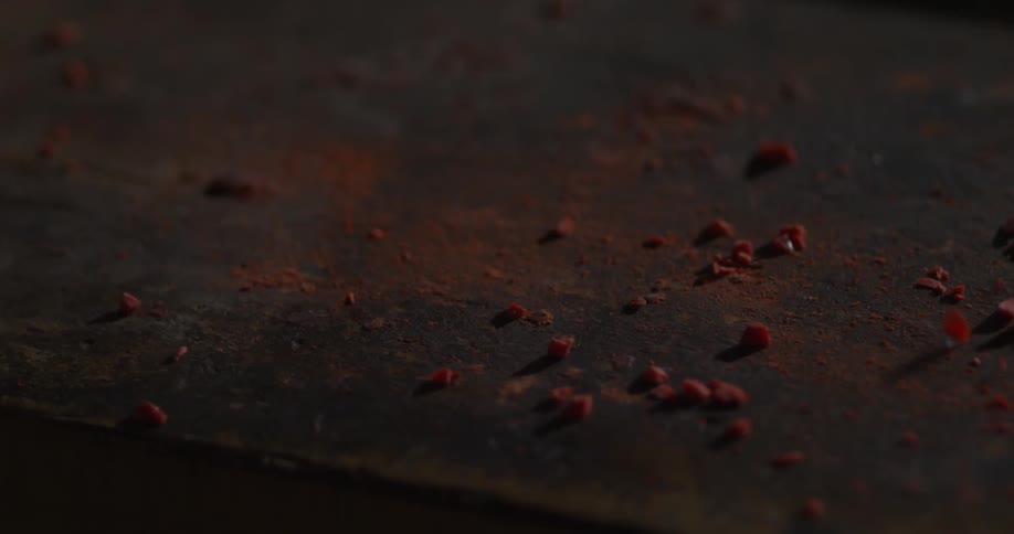 Red shavings blow across a tabletop