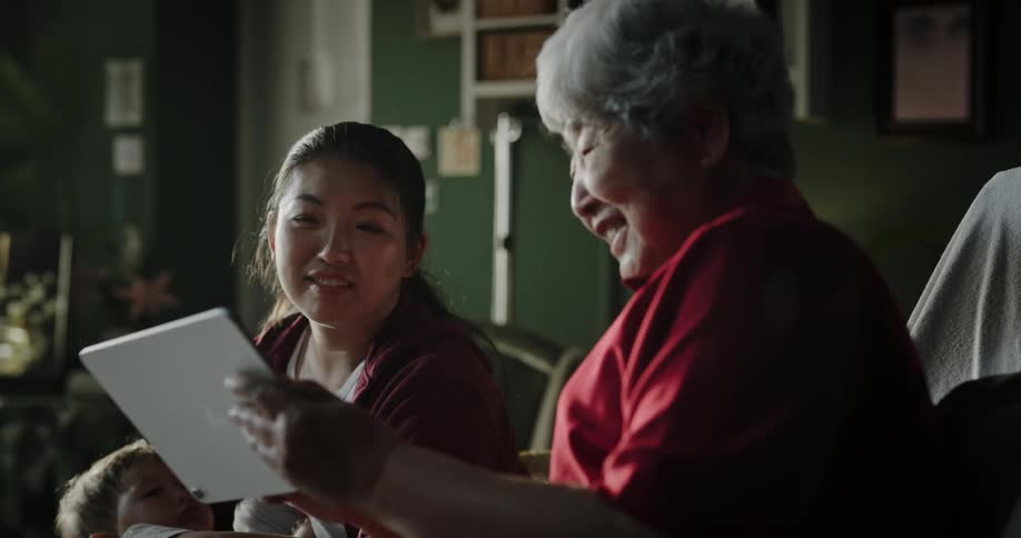 Grandmother using a tablet next to her daughter and baby grandson