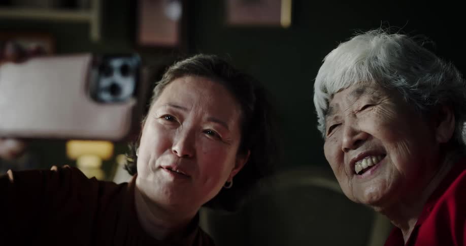 Portrait of two women having a conversation with someone in a selfie through a cellphone