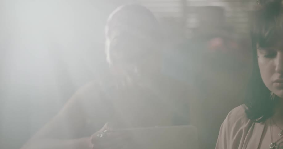 Two teenagers talk and use a tablet