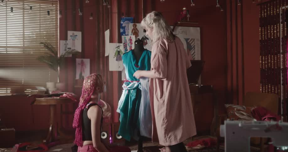 A clip of two ladies contemplating on how to dress a mannequin