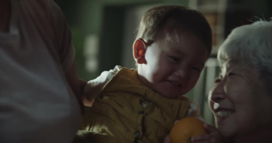 Grandmother plays with her grandson with an orange
