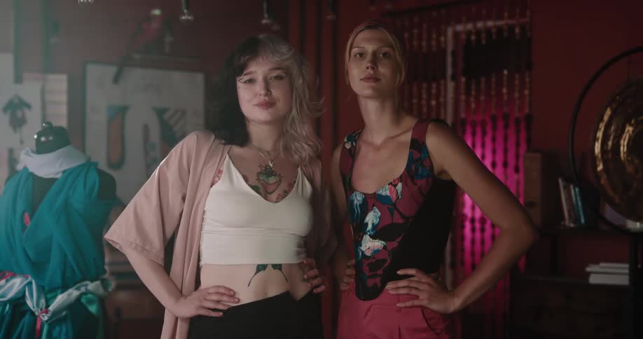 Two female designers stand posing in fashion studio