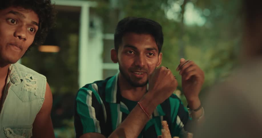 Two young men talking to someone smiling and crossing their fists in front of their chests