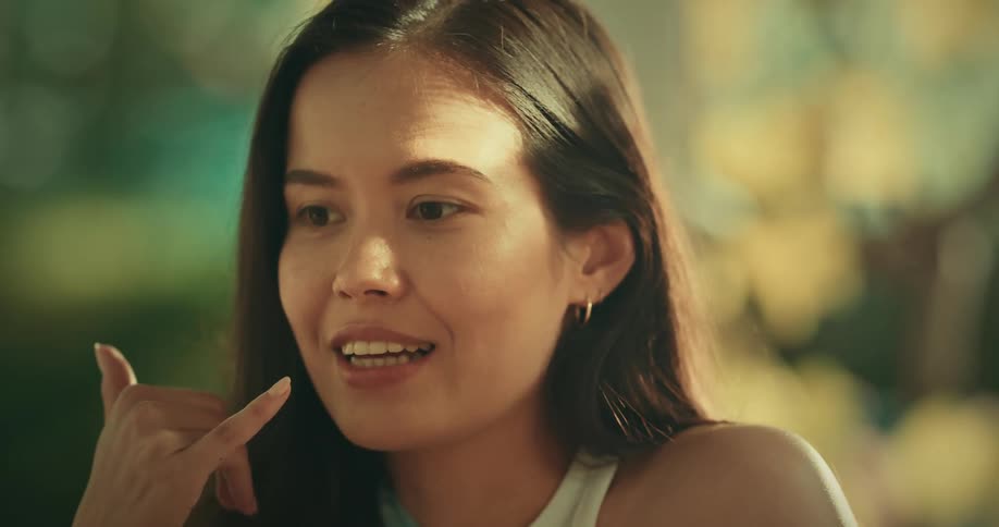 Woman with straight and white shirt talks with person smiling