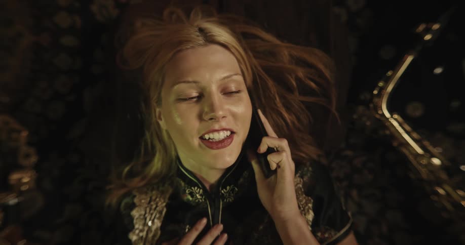 Portrait of a young blonde woman lying on the floor chatting on her cellphone with a smile