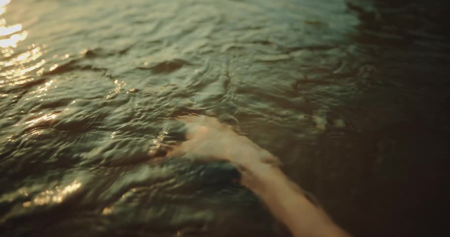 Hand moves underwater sun flare
