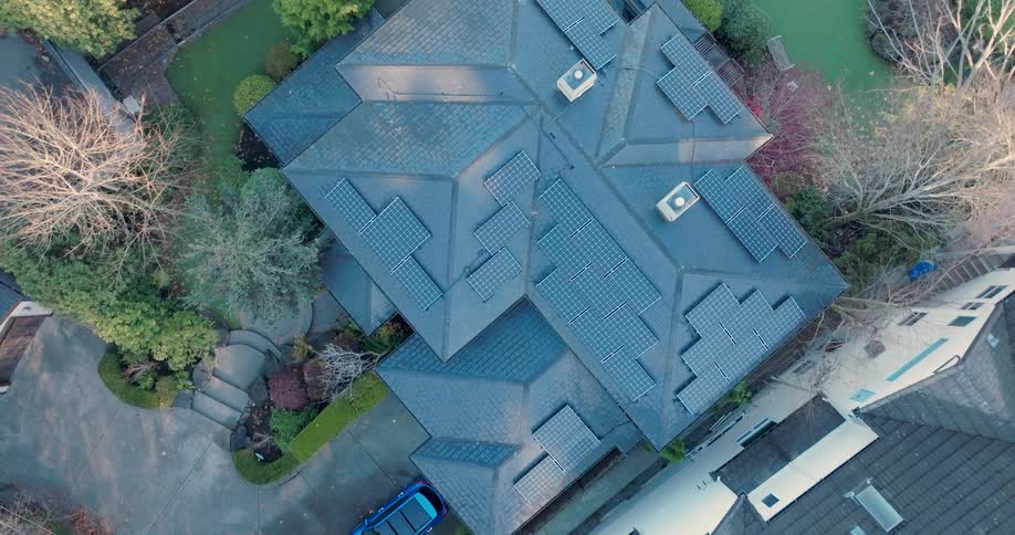 Twisting ascent over an upscale home with a slate roof fitted with a solar panel array
