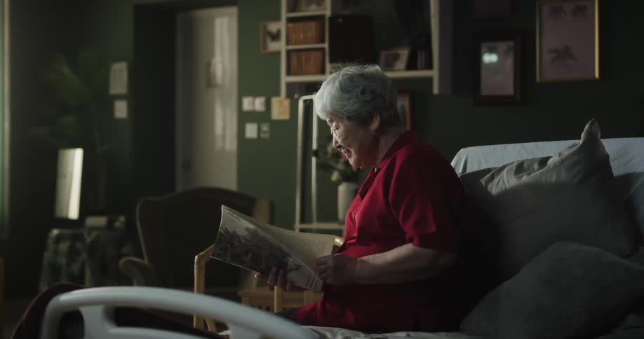 A clip of an elderly asian woman reading a magazine