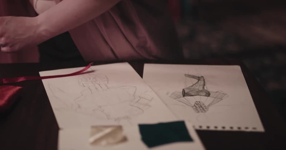 A tailor is looking at drawings of her designs
