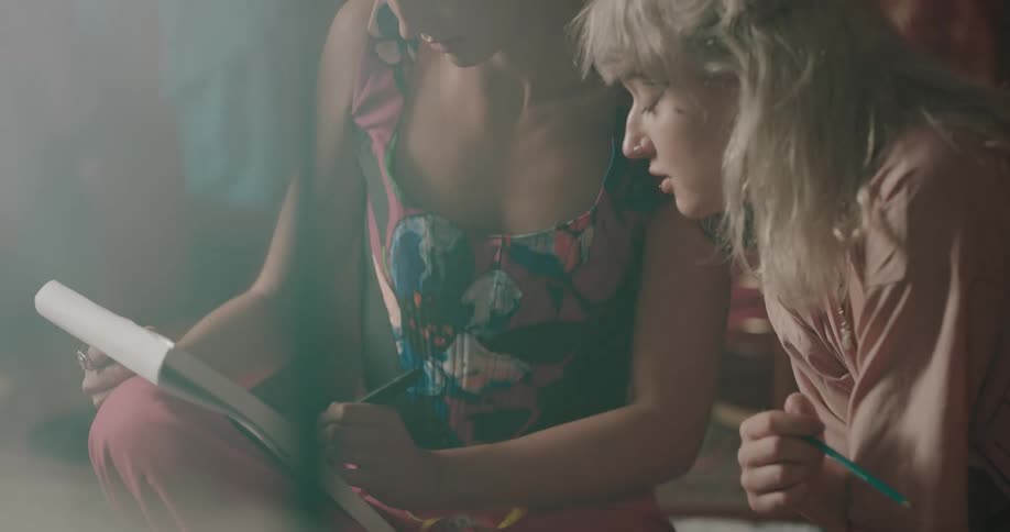 Two women look at a pad and talk