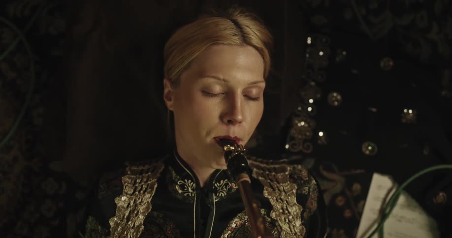 Woman lying down and playing a trumpet