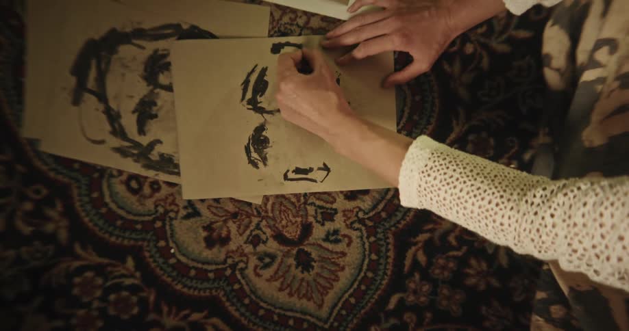 Female sketch artist drawing a face sketch on a paper placed on the floor indoor