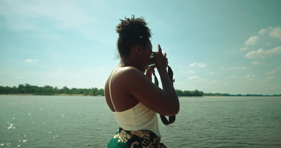 Woman walking amidst the sand of a lake and taking photos