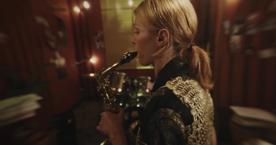 Portrait of a young blonde female musician playing a trumpet