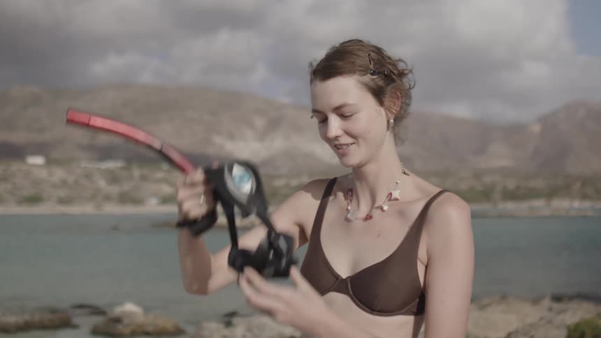 Woman in brown bikini puts on a pair of goggles
