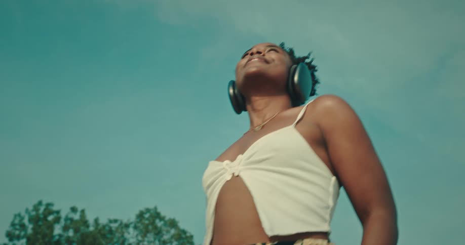 Black woman wearing headphones moves and dances outdoors