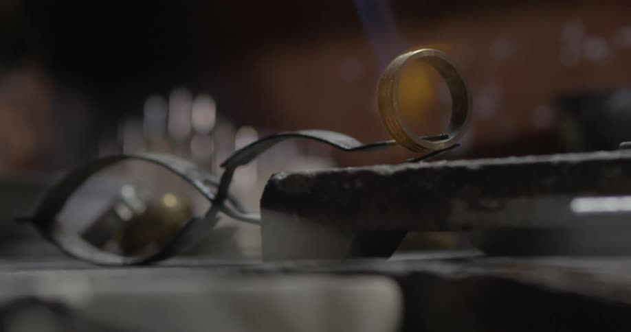 A ring maker uses a torch on a gold ring