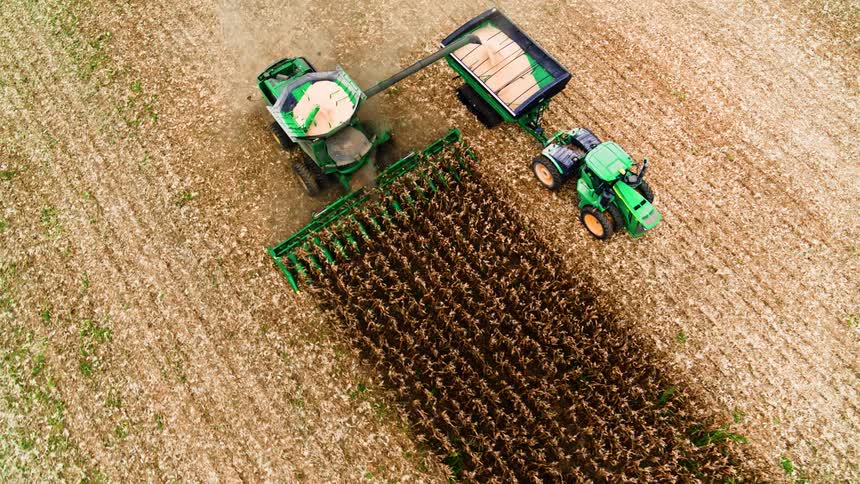 Tractors working efficiently to harvesting grain on a small farm in rural America