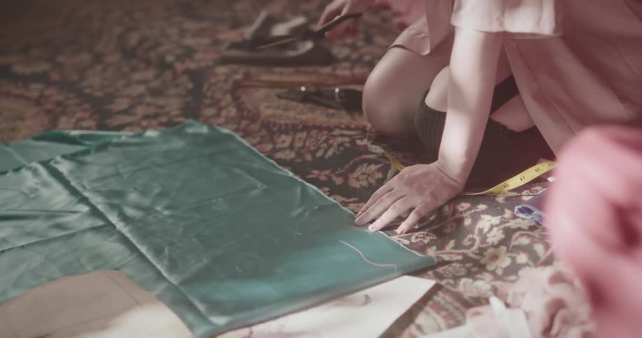 A tailor is cutting fabric with scissors